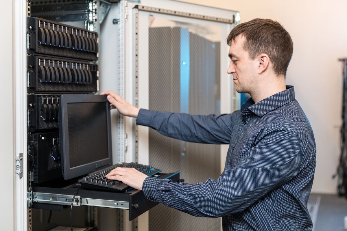 IT engineer with the management console between the server racks in the data center